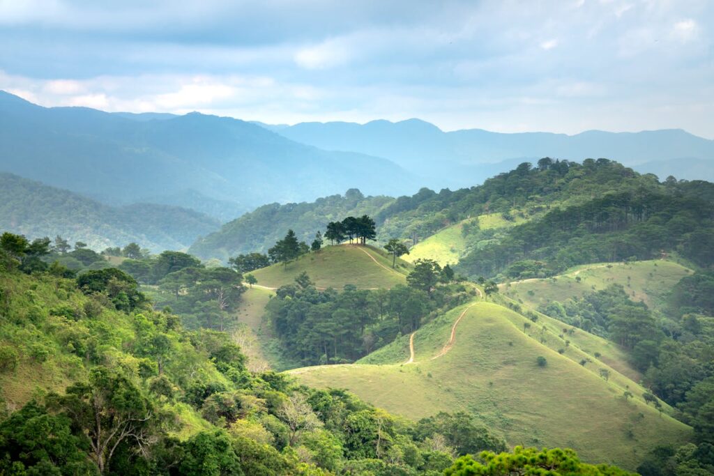 pexels-photo-4268127 Breathtaking view of lush green hills and a majestic mountain range under a cloudy blue sky.